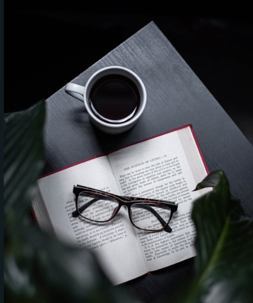 A book on the table with a coffee cup and reading glasses, symbolizing thoughtful book reviews and literary insights.