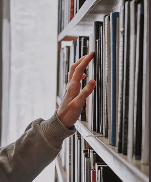 Person selecting a book from a bookshelf, representing carefully chosen editor’s picks and recommended reads.