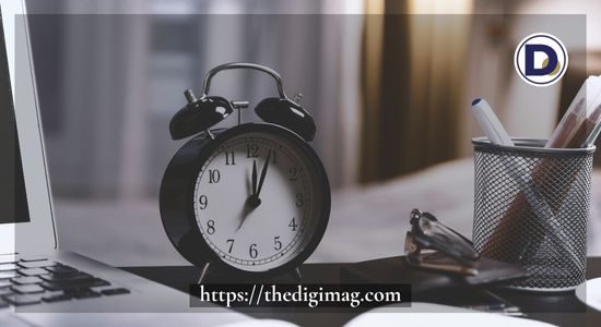 Table clock beside a computer symbolizing productivity and effective time management